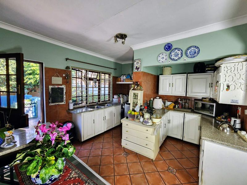 A functional kitchen featuring granite countertops, double basin sink, and ample built-in cabinetry, with direct access to an outdoor area.