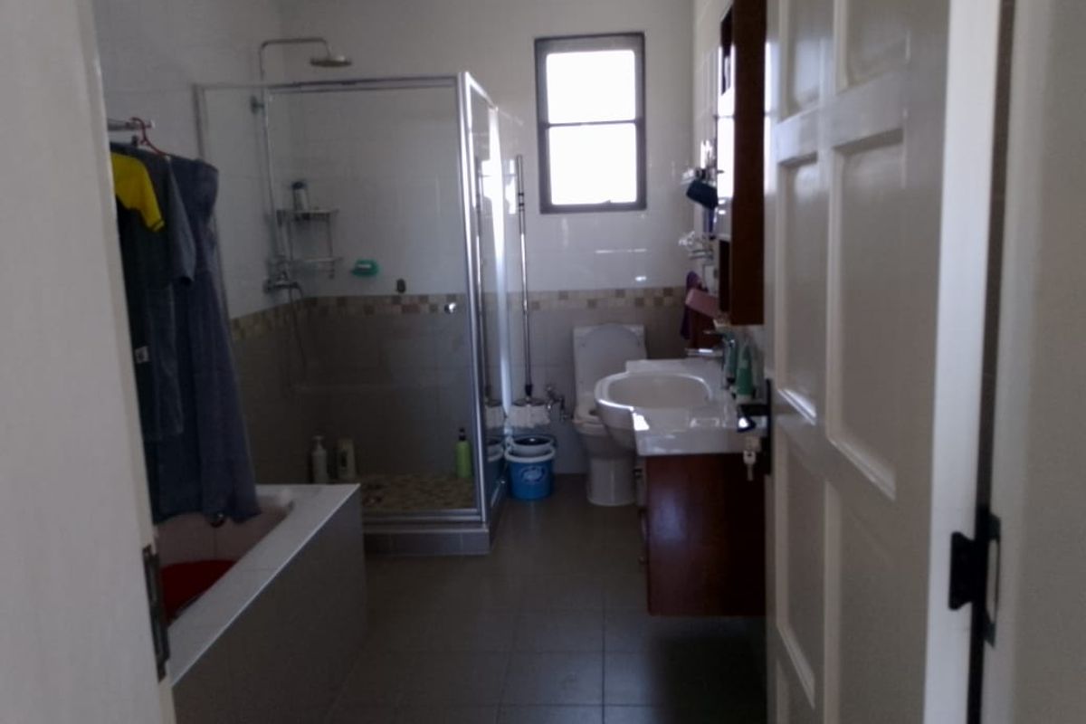 A functional bathroom featuring a glass-enclosed shower, a separate bathtub, a wall-mounted vanity, and a toilet.