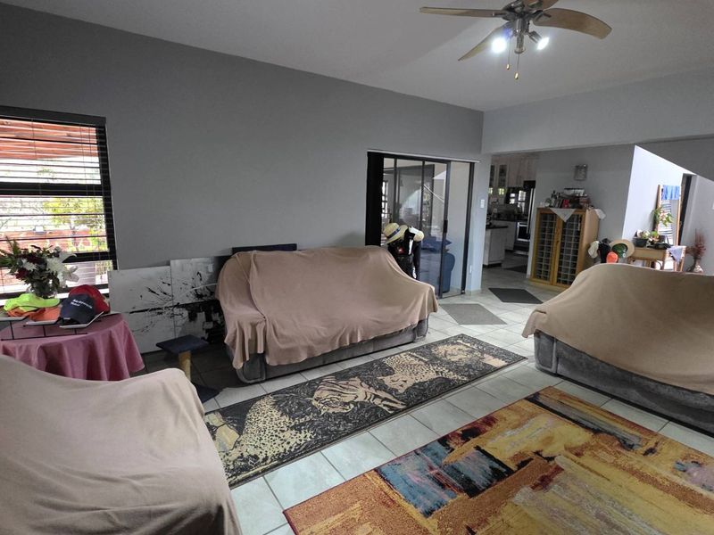 Spacious open-plan living area featuring tiled flooring, a ceiling fan, and sliding glass doors leading to an adjacent space.