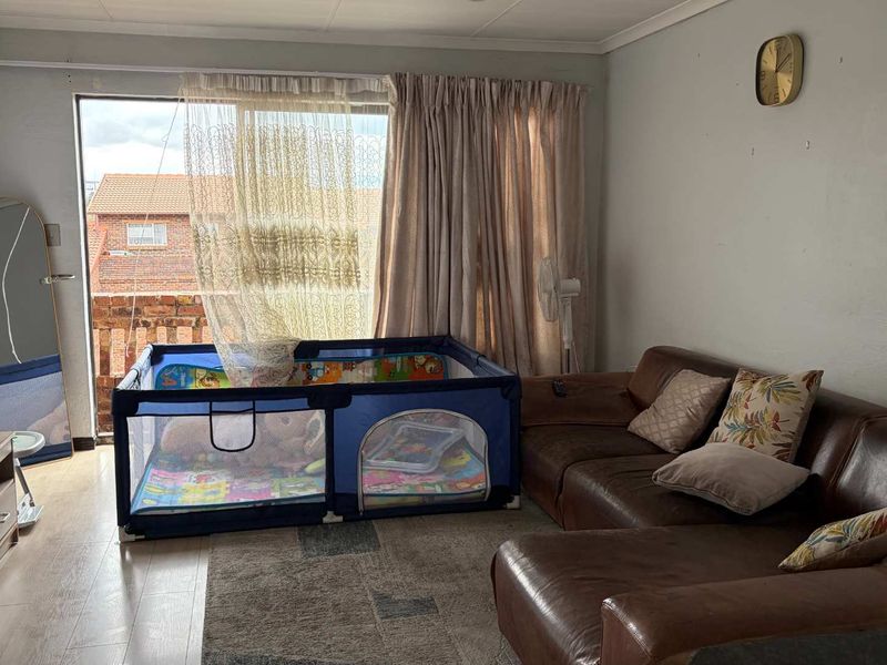 A living room featuring laminate flooring and a large sliding glass door that provides access to an outdoor balcony area.
