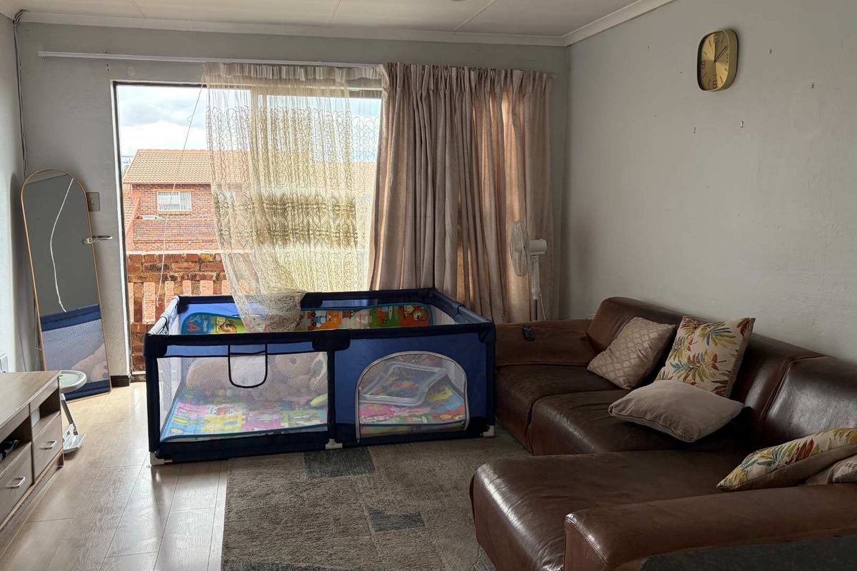 A living room featuring laminate flooring and a large sliding glass door that provides access to an outdoor balcony area.