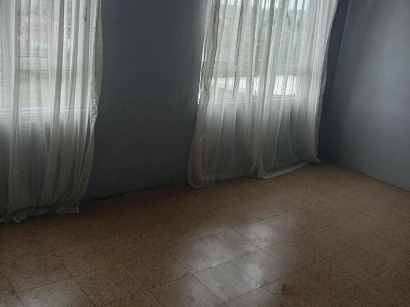 An empty bedroom featuring tiled flooring and a timber-paneled ceiling, offering a blank canvas for renovation or interior design updates.