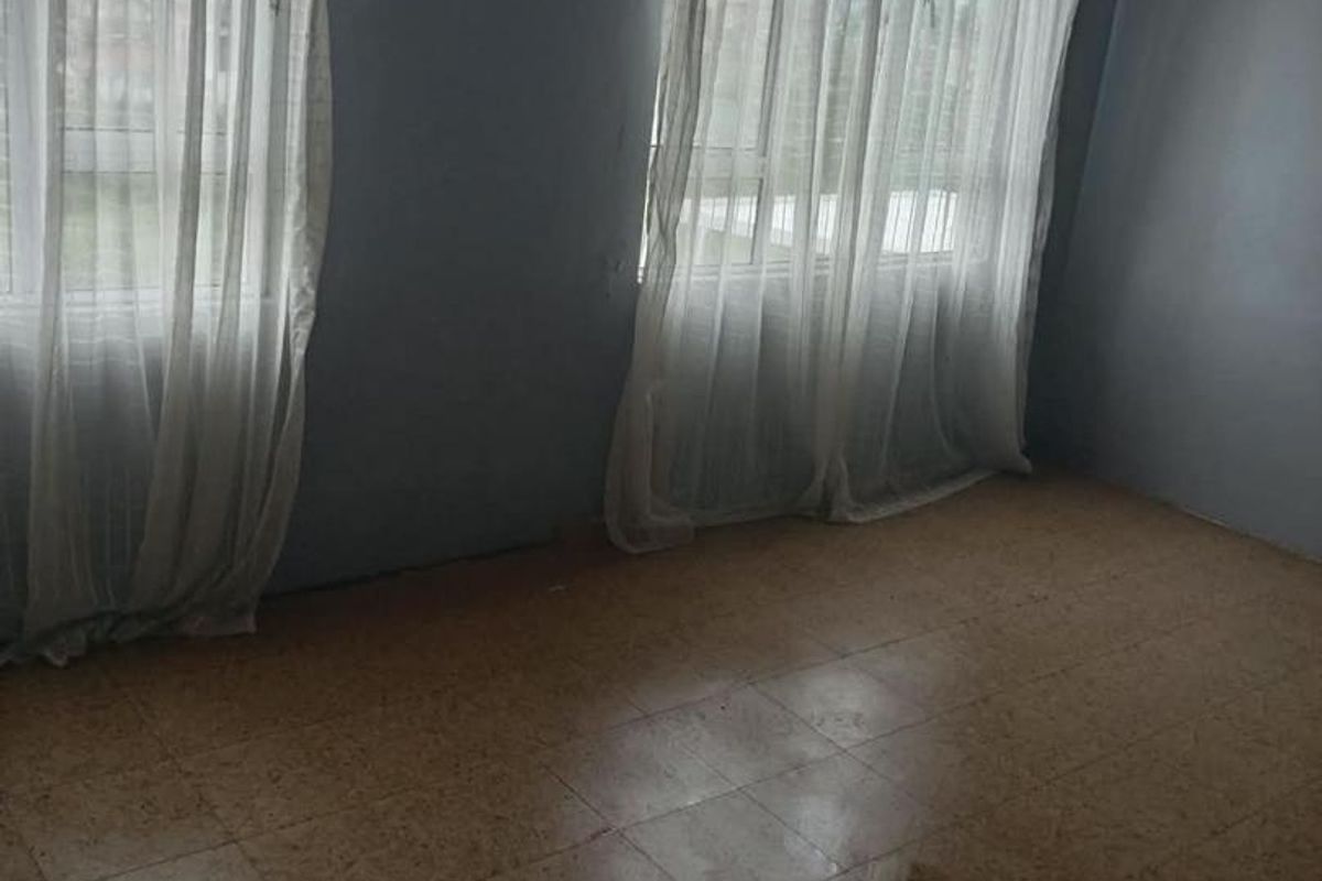 An empty bedroom featuring tiled flooring and a timber-paneled ceiling, offering a blank canvas for renovation or interior design updates.