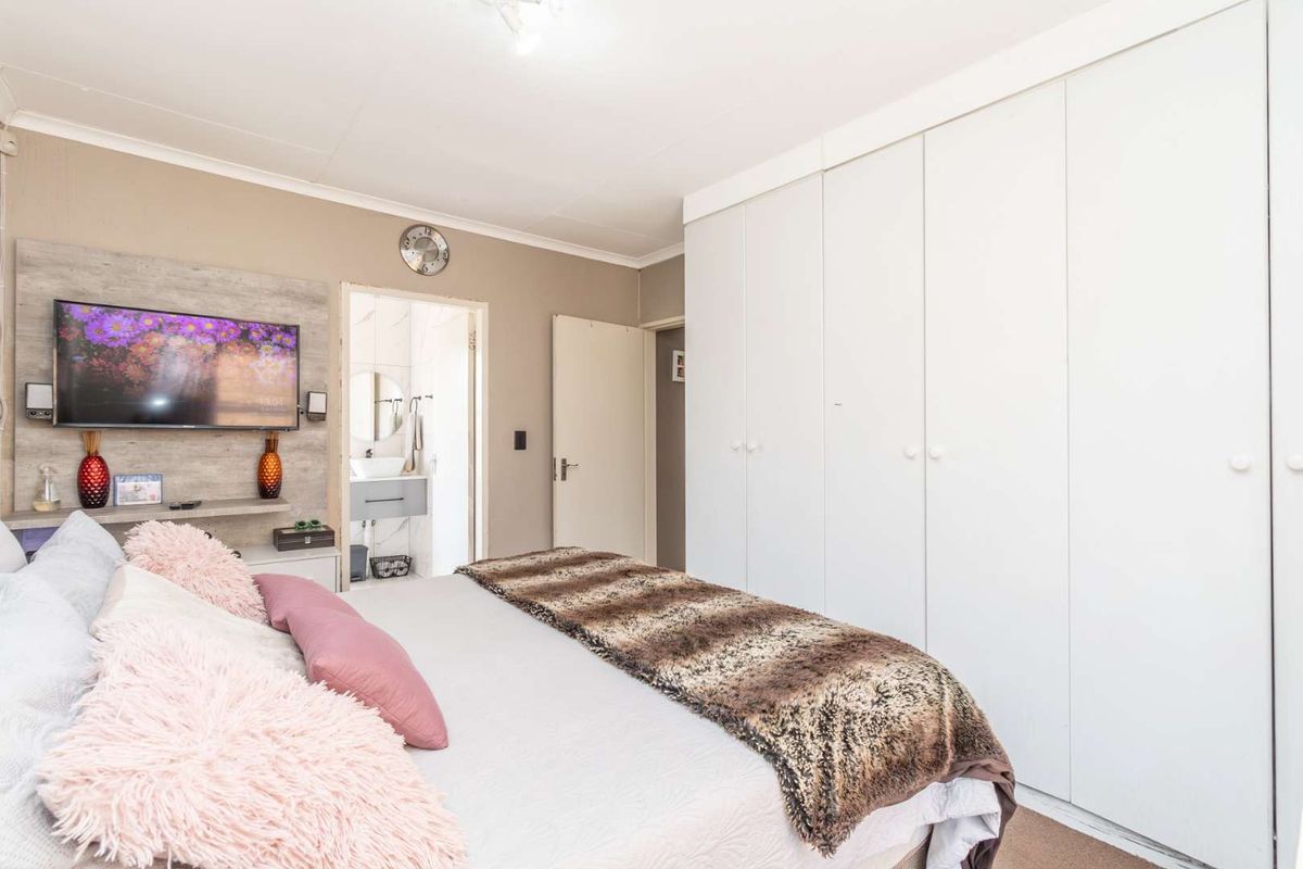 A well-lit bedroom featuring extensive built-in floor-to-ceiling wardrobes and an en-suite bathroom access.