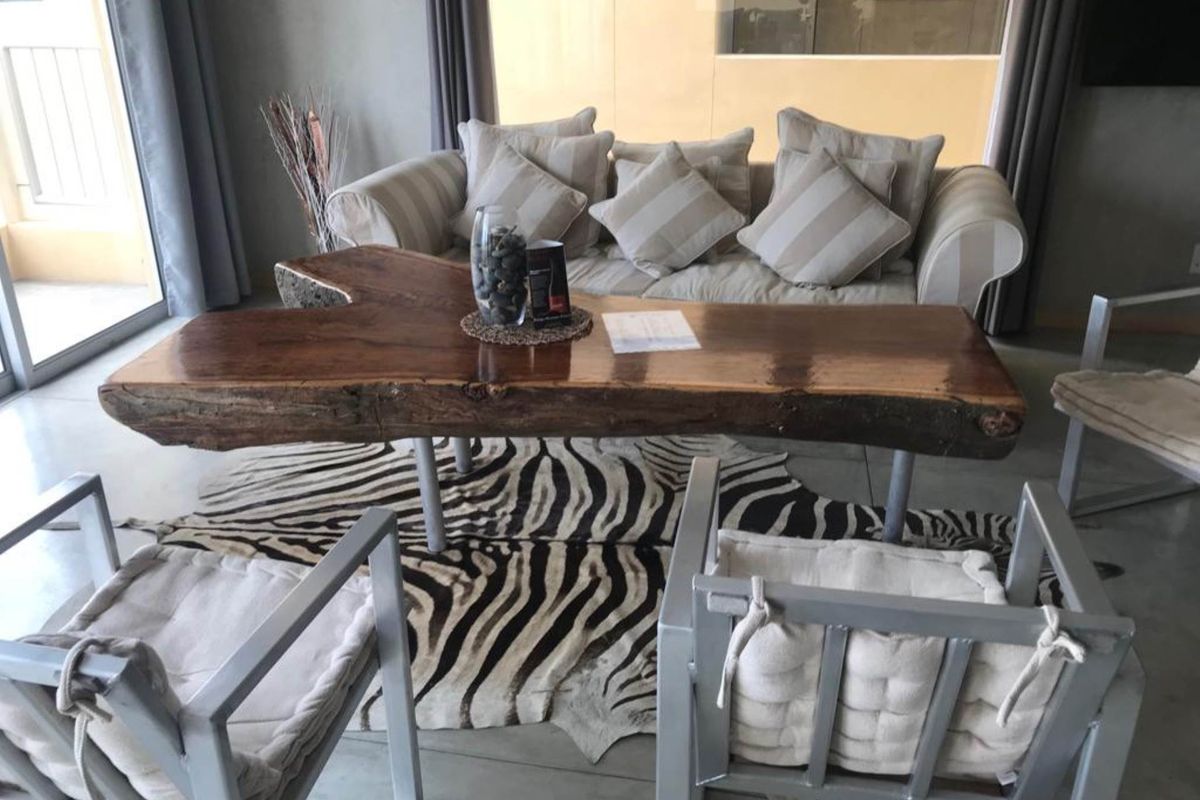 A comfortable living room area featuring polished concrete flooring and large windows that provide natural light and access to an outdoor patio space.