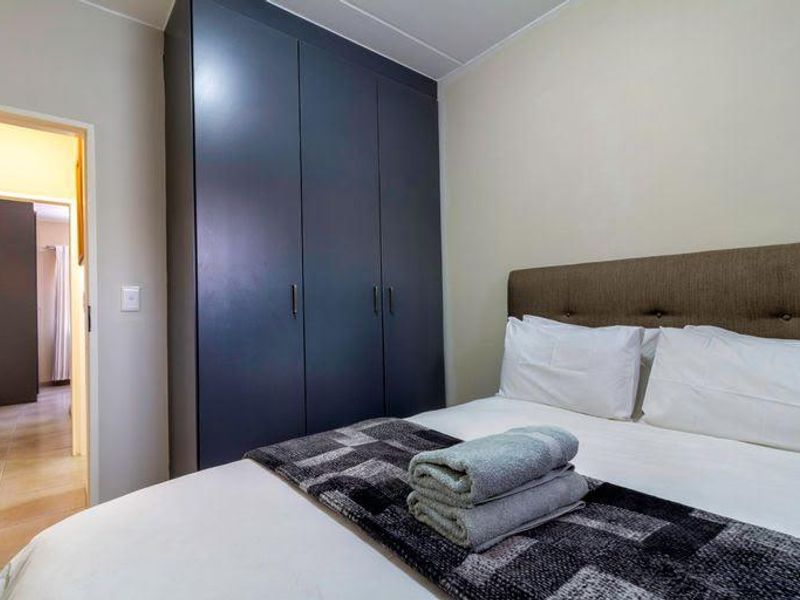 A well-maintained bedroom featuring a dark built-in wardrobe and neutral wall finishes, providing a clean and functional sleeping space.