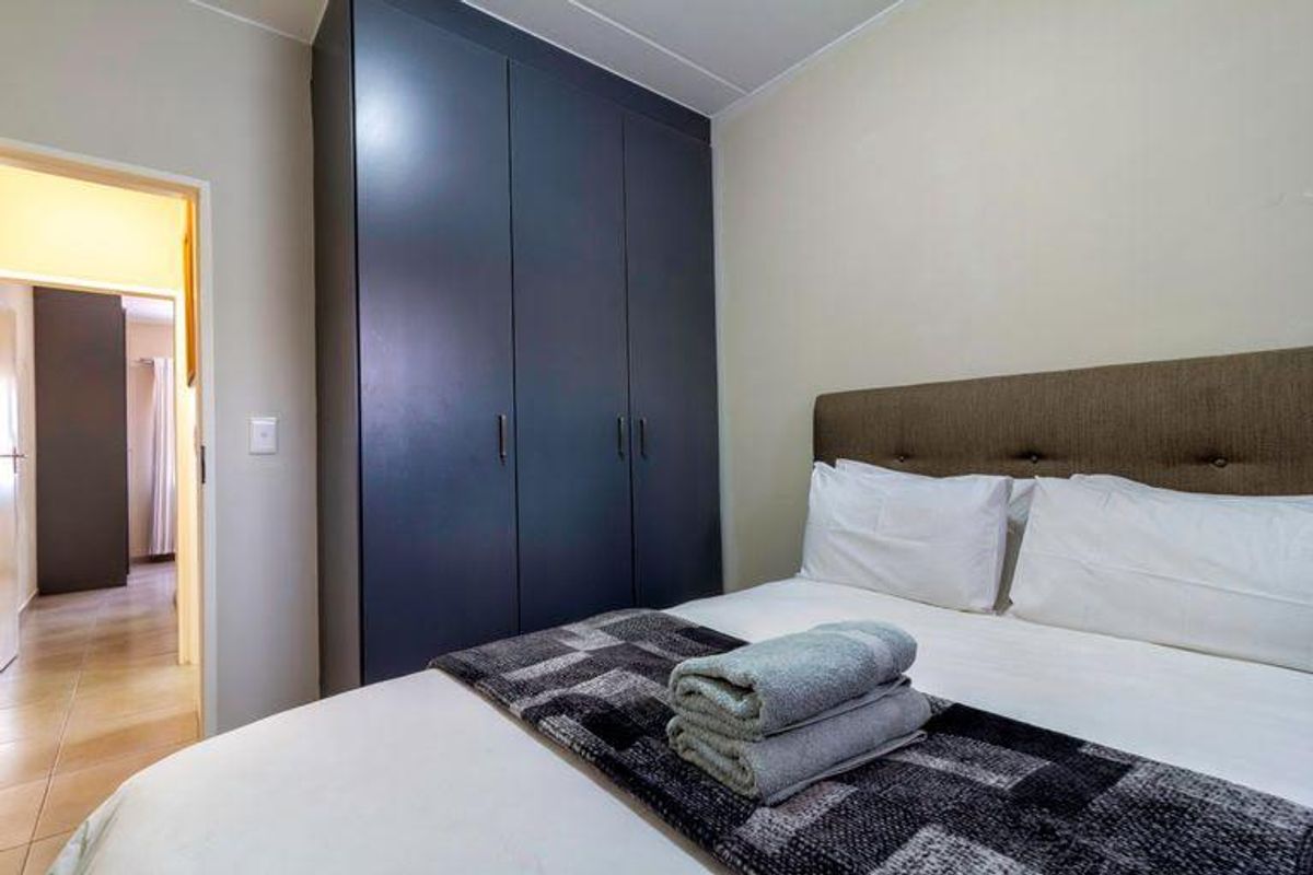 A well-maintained bedroom featuring a dark built-in wardrobe and neutral wall finishes, providing a clean and functional sleeping space.