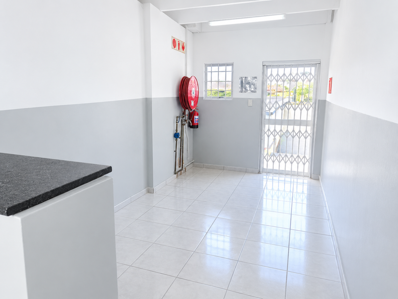 A clean, functional utility space featuring tiled flooring, a security gate, and essential fire safety equipment including a hose reel and extinguisher.