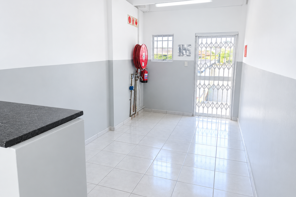 A clean, functional utility space featuring tiled flooring, a security gate, and essential fire safety equipment including a hose reel and extinguisher.