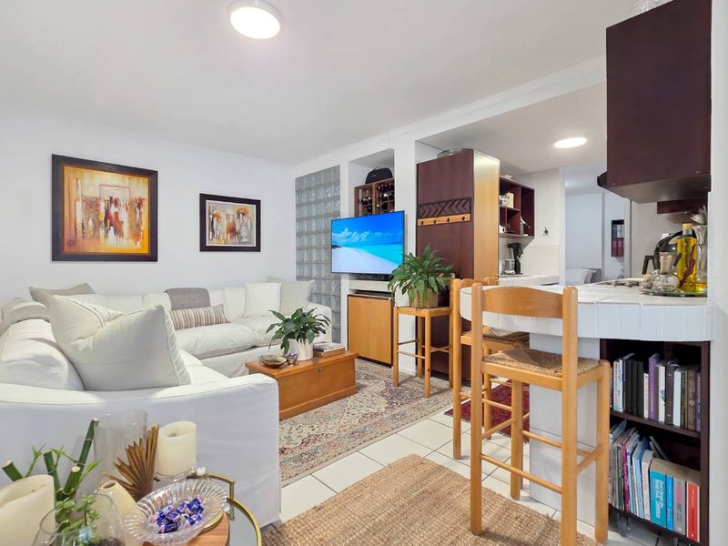 Open-plan living area featuring tiled floors, a breakfast bar, and a unique glass block feature wall, seamlessly connecting to the kitchen space.