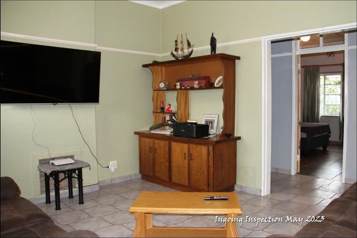 A living room featuring tiled flooring, picture rails, and a doorway leading to an adjacent bedroom.