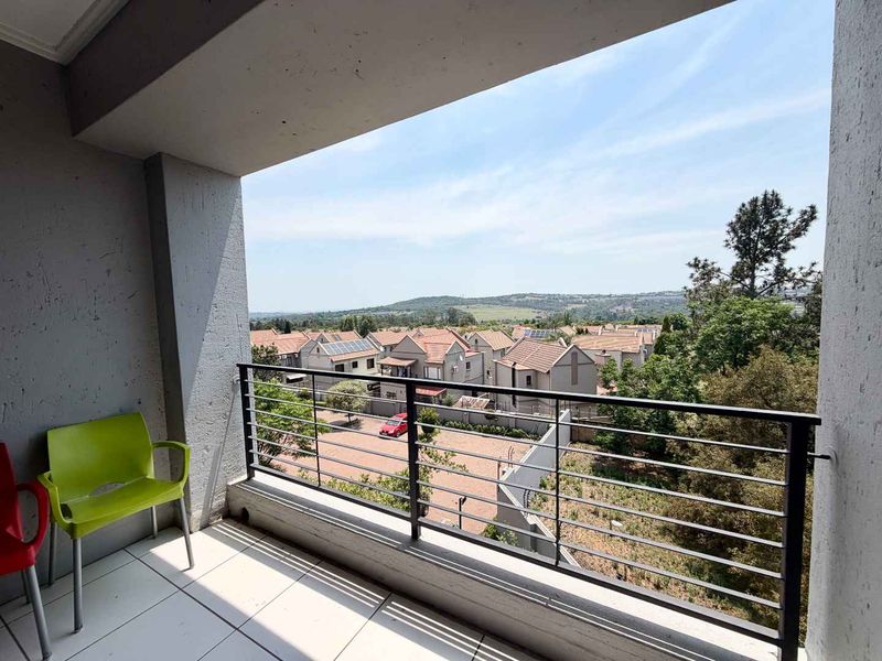 A covered balcony featuring tiled flooring and a metal safety railing, offering an elevated view of the surrounding residential neighborhood.