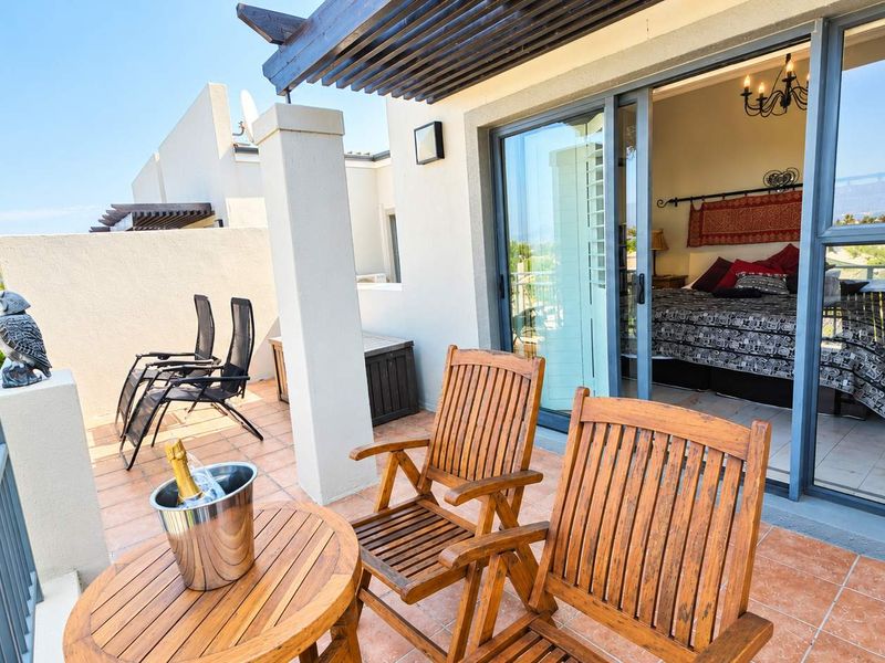 A covered balcony featuring tiled flooring, a timber pergola, and sliding glass doors providing seamless access to the bedroom.