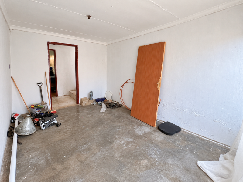 An unfinished utility space featuring concrete flooring and plain walls, suitable for storage or conversion into a functional room.