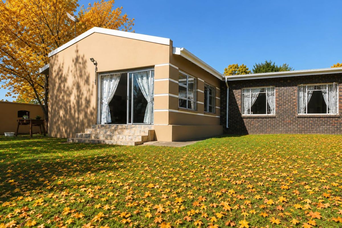 Rear view of the house featuring a lawn, brick and rendered facade, sliding glass doors, and stone-tiled steps leading to the garden.