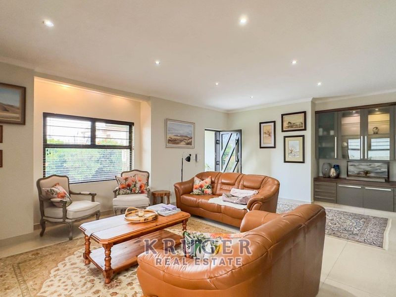 Spacious living room featuring tiled flooring, recessed downlighting, and custom built-in cabinetry, offering a comfortable and well-maintained area for relaxation.