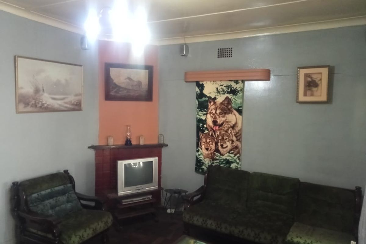 A living room featuring a brick fireplace surround and parquet flooring, offering a traditional layout with potential for modernization.