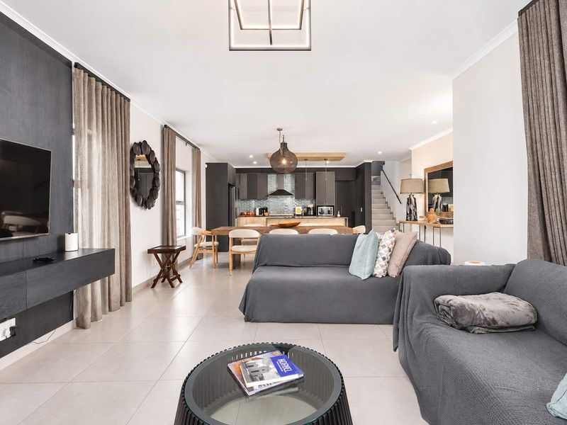 Spacious open-plan living area featuring a modern kitchen with island, sleek cabinetry, and tiled flooring, seamlessly flowing into the lounge space.
