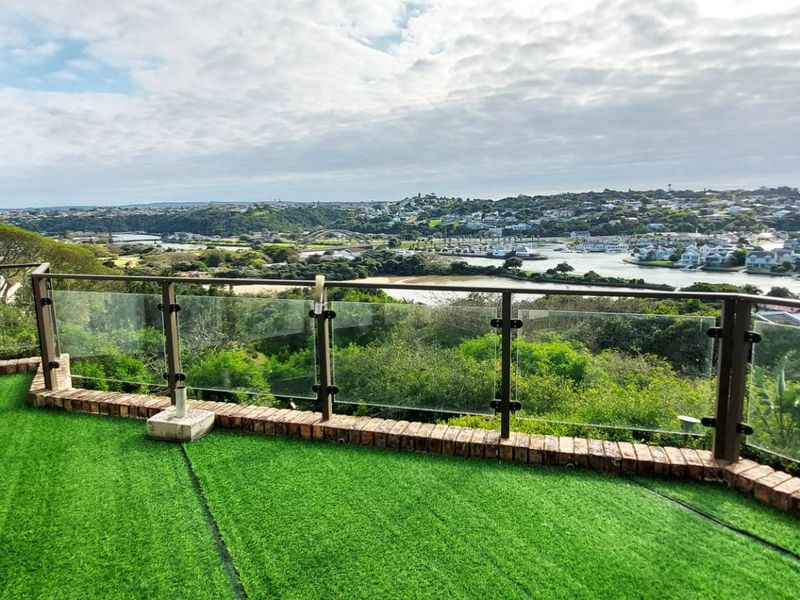 Elevated balcony featuring a glass balustrade, brick edging, and artificial turf, offering expansive views of the surrounding landscape and river.