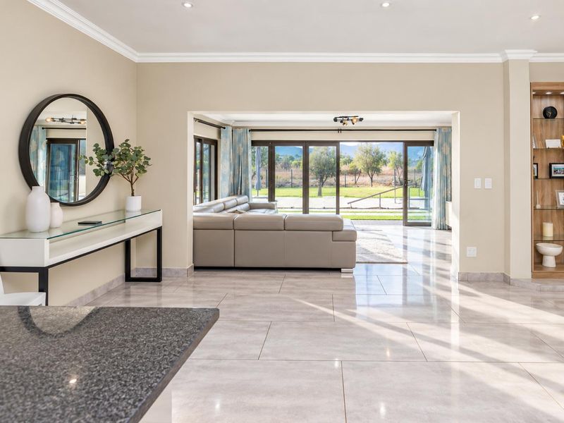 Spacious open-plan living area featuring large format floor tiles, recessed lighting, and seamless access to the outdoor patio through sliding glass doors.