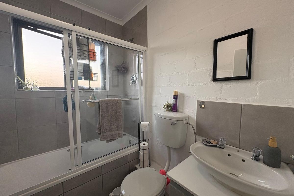 A functional bathroom featuring a combined shower and bathtub, a vanity basin, and a toilet with a high-level cistern.