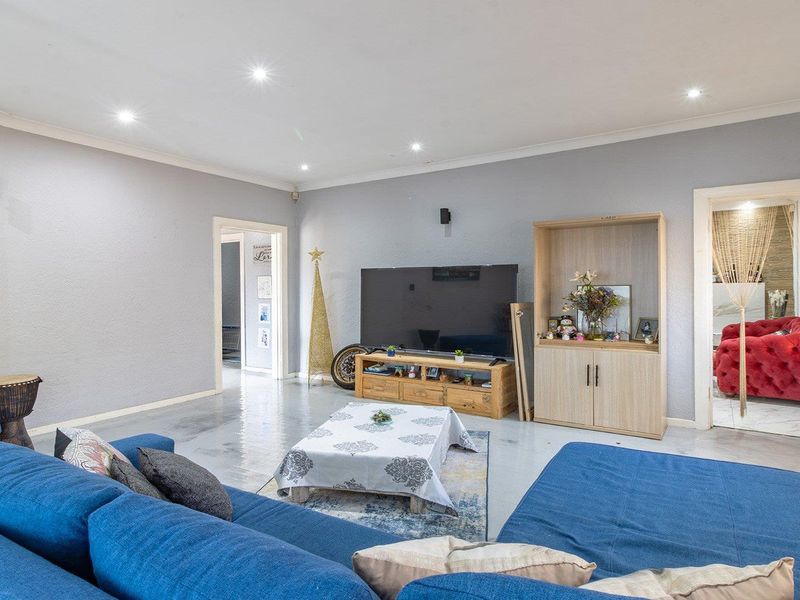 Spacious living room featuring neutral grey walls, recessed downlighting, and built-in cabinetry, providing a comfortable and well-lit area for relaxation.