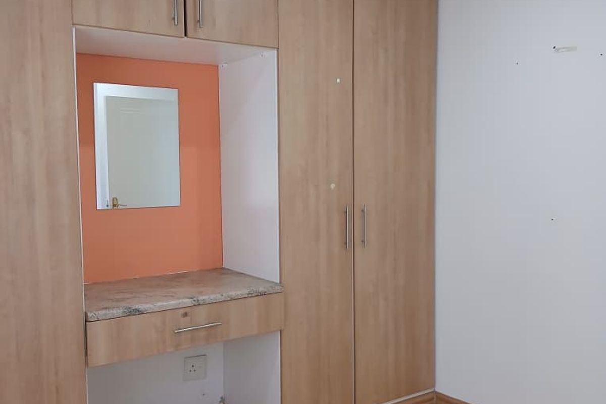 Bedroom featuring built-in light wood cabinetry with an integrated vanity station, stone countertop, and light-toned laminate flooring.