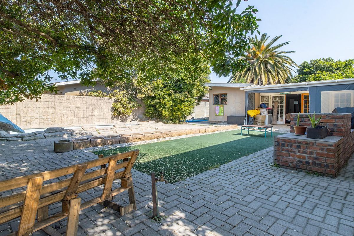 Rear garden area featuring brick paving, artificial turf, and a built-in brick braai, offering a functional outdoor entertainment space.