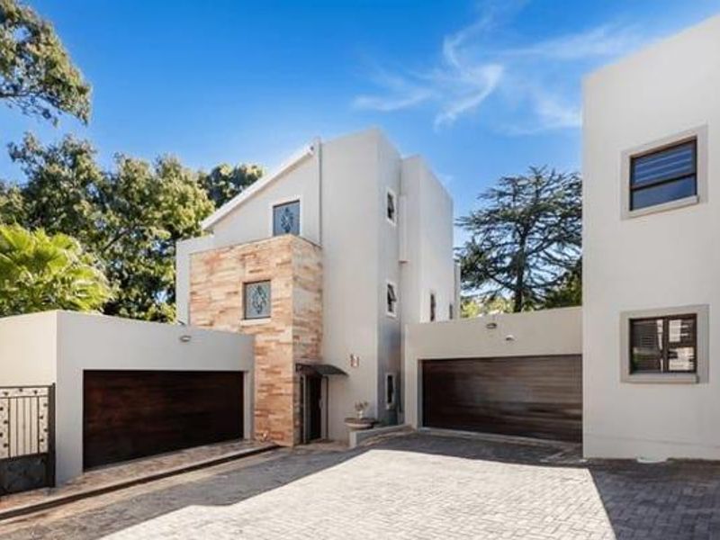 Modern townhouse exterior featuring a paved driveway, double garage doors, and attractive stone cladding accents on the facade.
