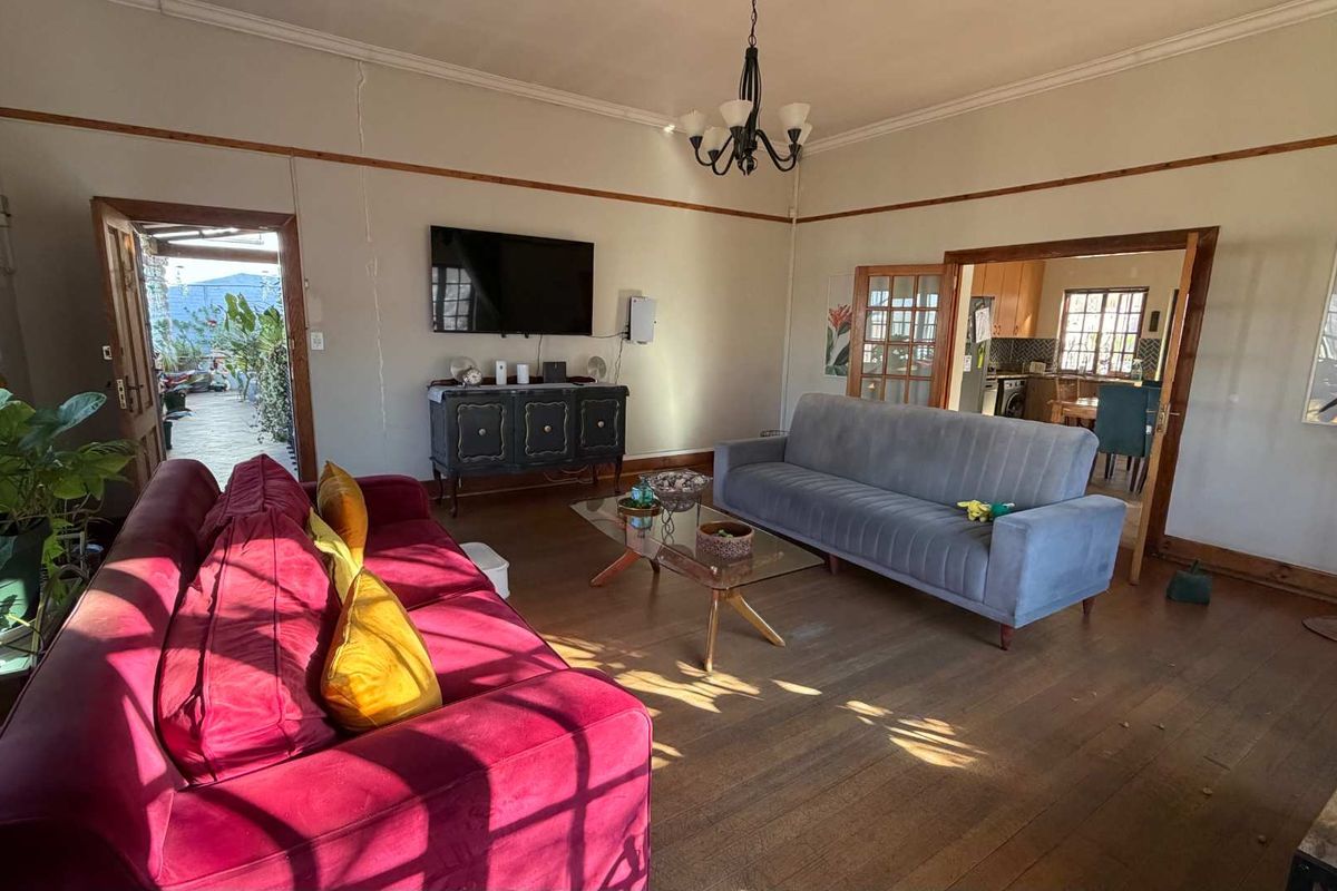 Spacious living room featuring original timber flooring, high ceilings with crown molding, and direct access to an outdoor patio area.
