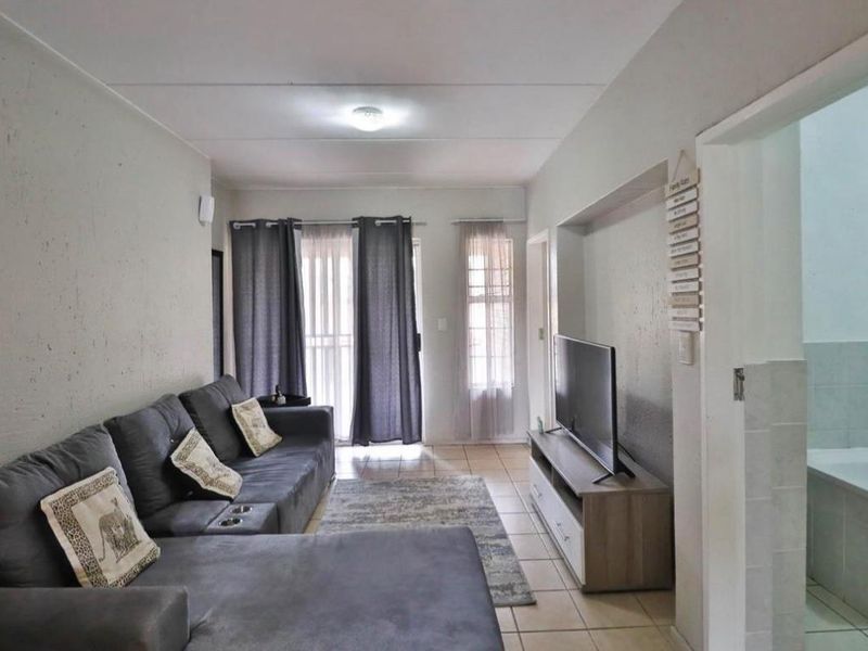A living room featuring tiled flooring, a recessed wall niche, and a sliding glass door providing access to the exterior.