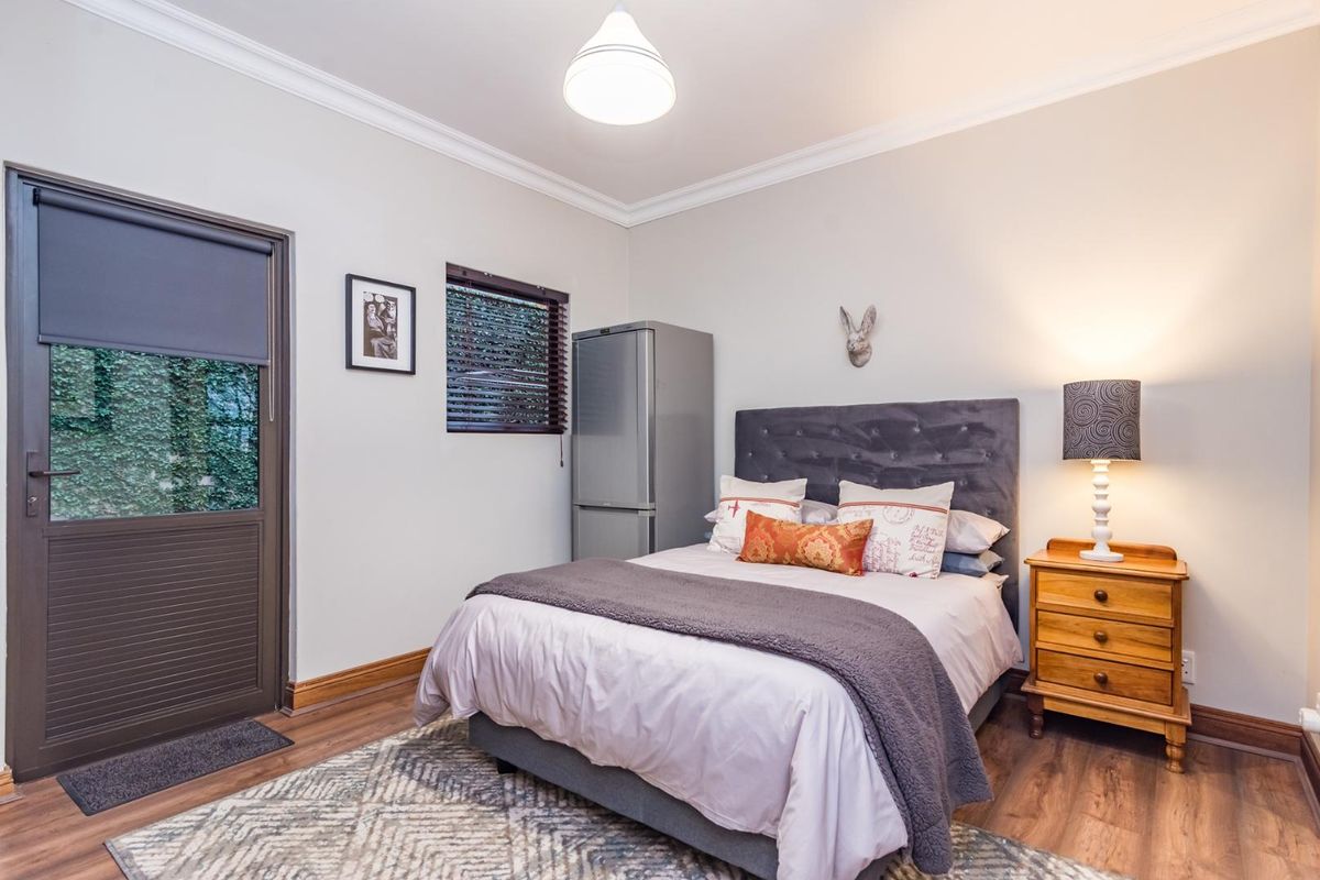 A well-maintained bedroom featuring laminate flooring, crown molding, and direct access to the exterior via a private door.