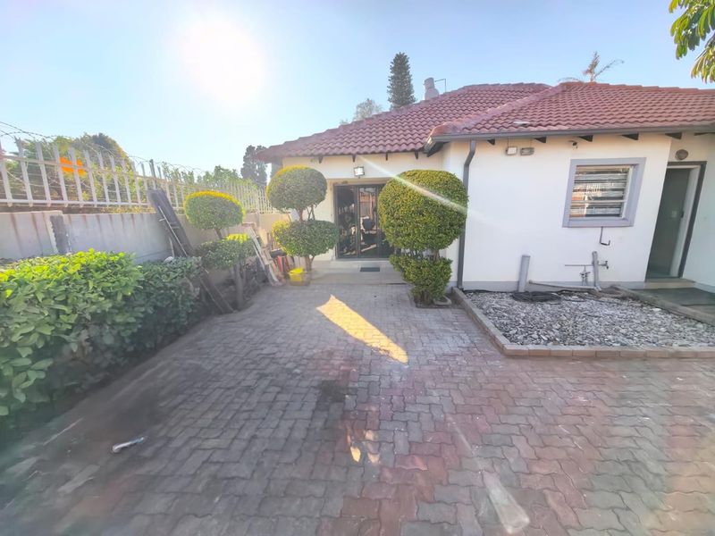 Rear exterior view of the property featuring a paved courtyard, tiled roof, and secure perimeter fencing.