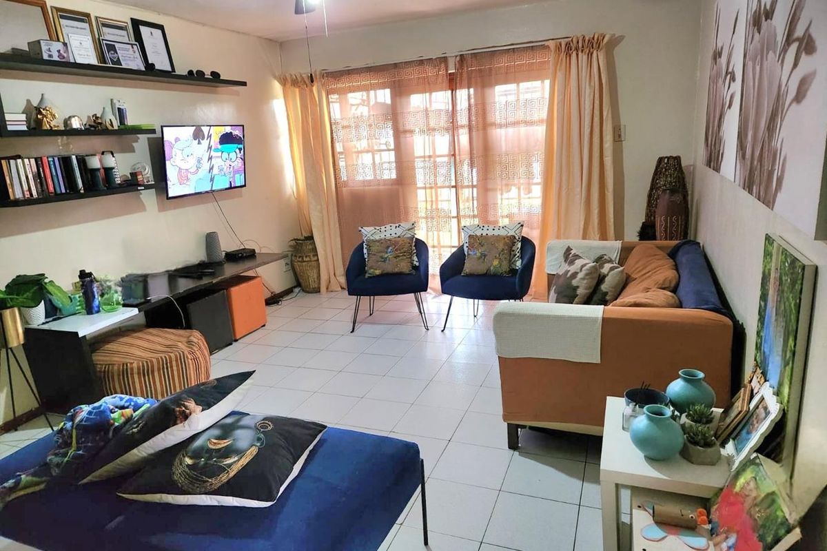 A living room featuring tiled flooring, a ceiling fan, and a sliding glass door providing access to the exterior.