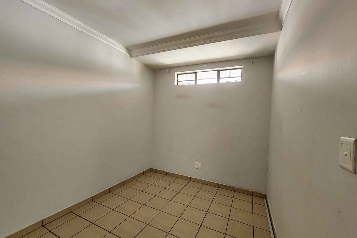 An empty bedroom featuring tiled flooring, a high-level window, and coved ceiling details, offering a blank canvas for personalization.