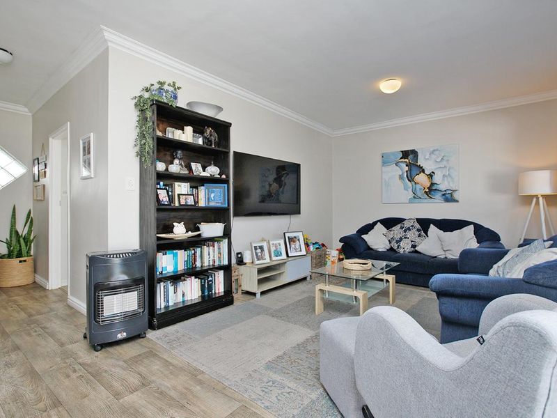A comfortable living room featuring crown molding, laminate flooring, and a unique diamond-shaped window, providing a functional and inviting space.