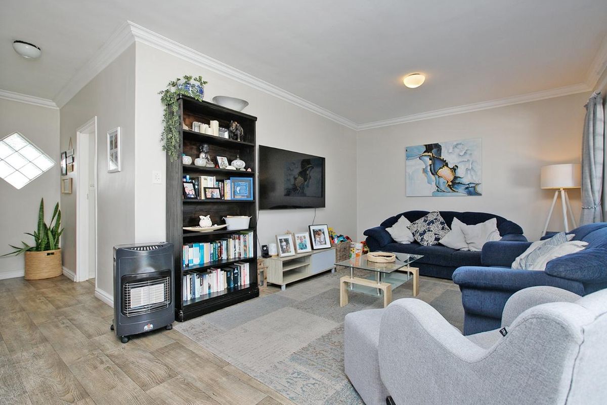 A comfortable living room featuring crown molding, laminate flooring, and a unique diamond-shaped window, providing a functional and inviting space.