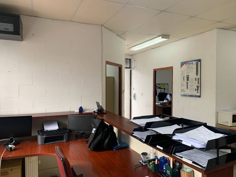 Functional office space featuring a built-in reception desk, drop ceiling with fluorescent lighting, and painted blockwork walls.