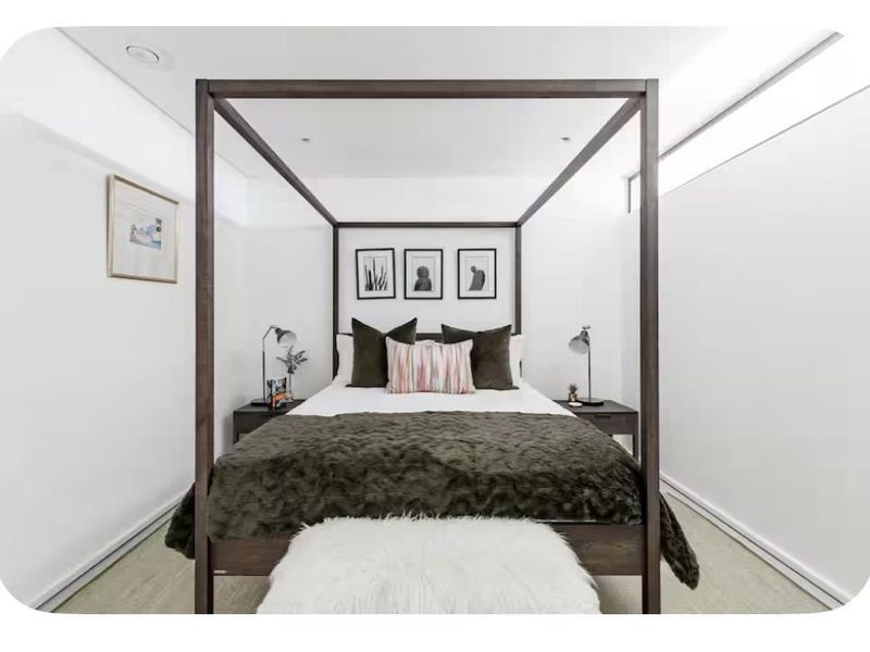 A well-maintained bedroom featuring clean white walls, recessed ceiling lighting, and high-level clerestory windows providing natural light.