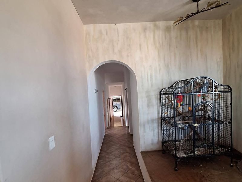 A transition hallway featuring stone tile flooring, an arched doorway, and textured wall finishes leading to an adjacent living space.