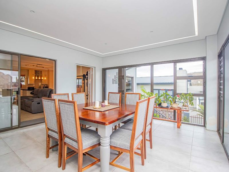 A bright, enclosed patio area featuring large sliding glass doors, tiled flooring, and modern recessed ceiling lighting, offering a seamless transition to the outdoors.