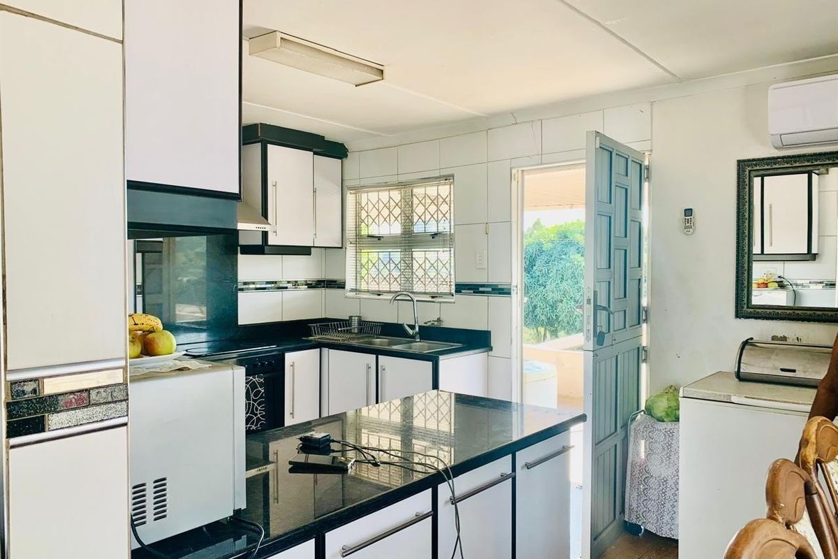 Functional kitchen featuring granite countertops, built-in cabinetry, and a tiled backsplash, with direct access to an outdoor area.