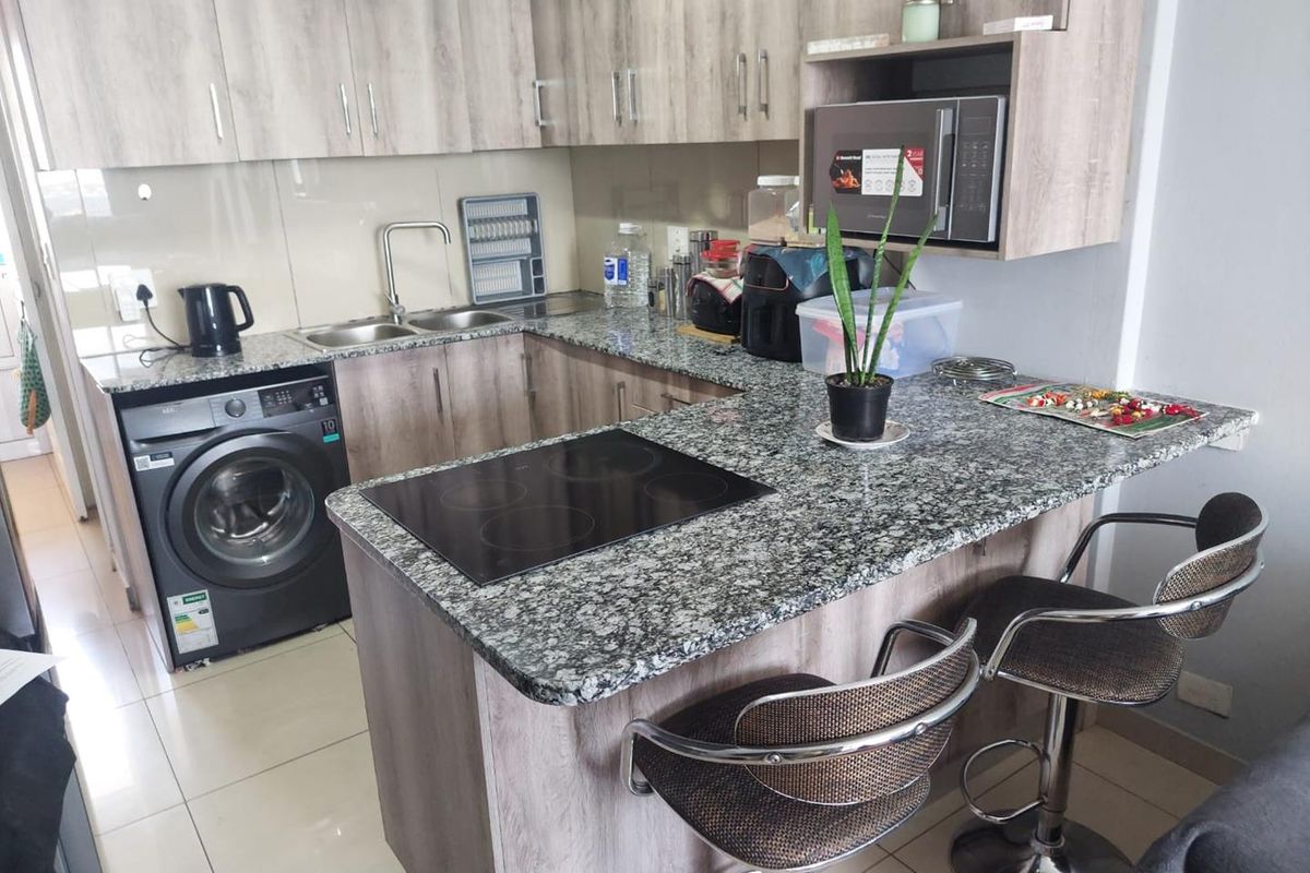 A functional kitchen featuring granite countertops, built-in cabinetry, an integrated electric hob, and a built-in microwave with tiled flooring.