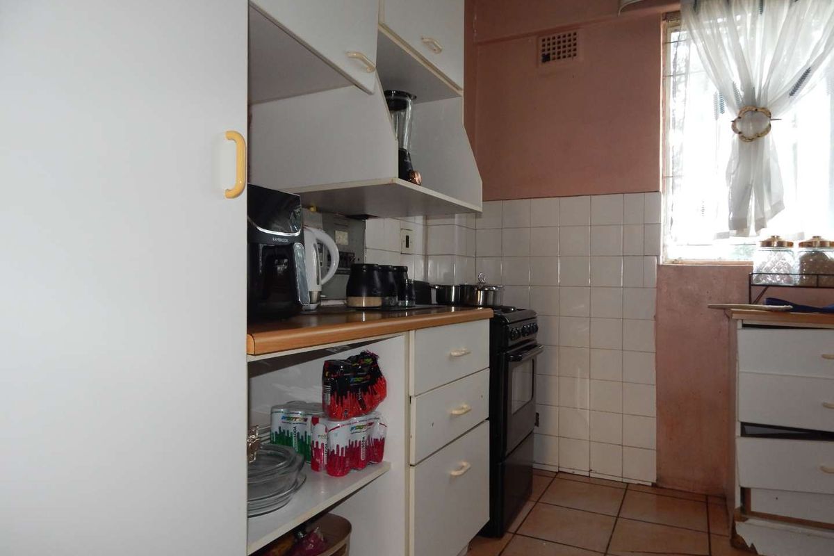 A compact kitchen featuring tiled flooring, a tiled splashback, and functional built-in cabinetry with a freestanding stove.
