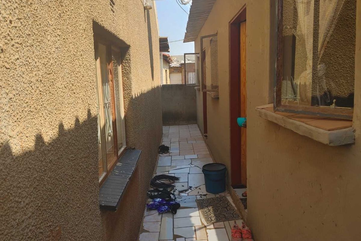 A narrow exterior side passage featuring tiled flooring and access to the side of the house.