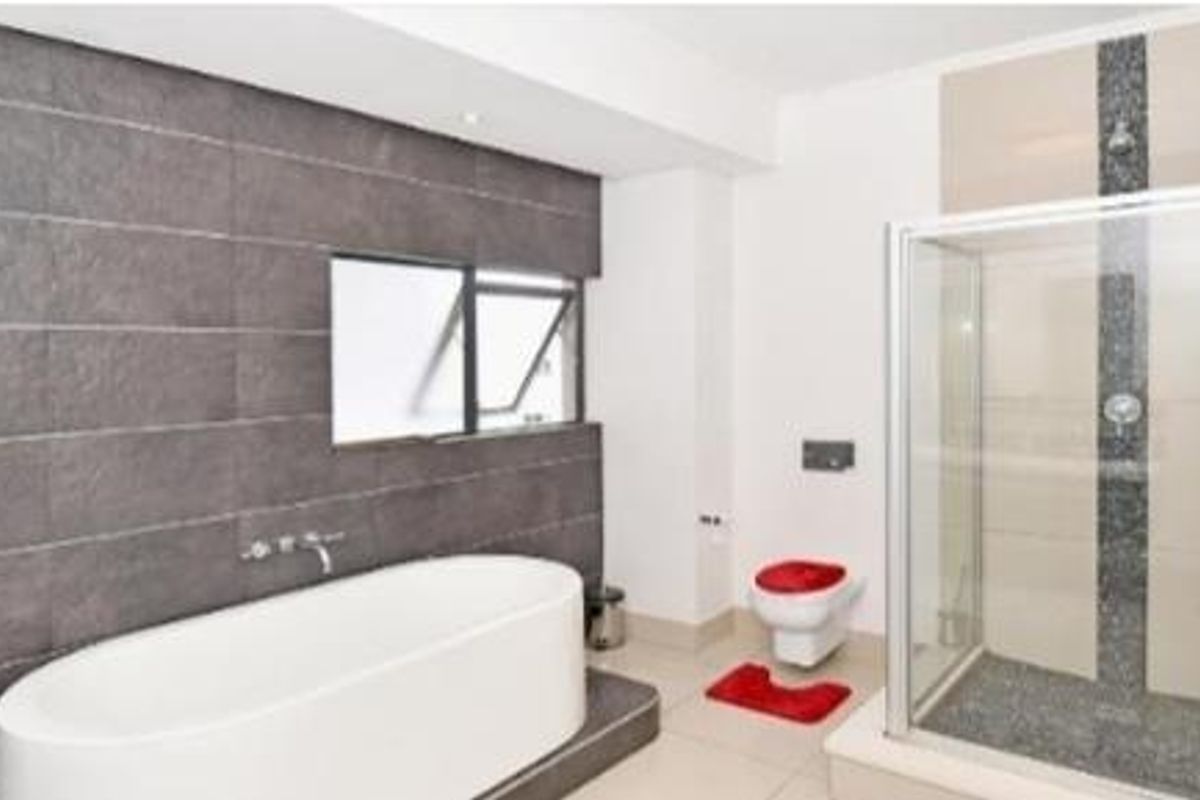 Modern bathroom featuring a freestanding bathtub, a separate glass-enclosed shower, and a stylish tiled feature wall.