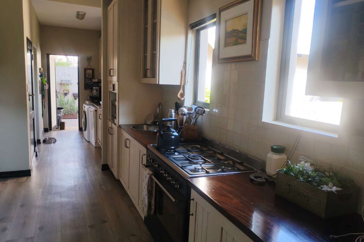 A functional kitchen featuring timber countertops, built-in cabinetry, a gas hob, and an oven, with direct access to a laundry area.