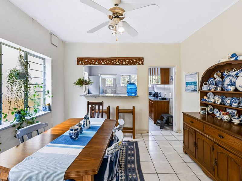 Dining room featuring tiled flooring, a ceiling fan, and a serving hatch connecting to the kitchen area.