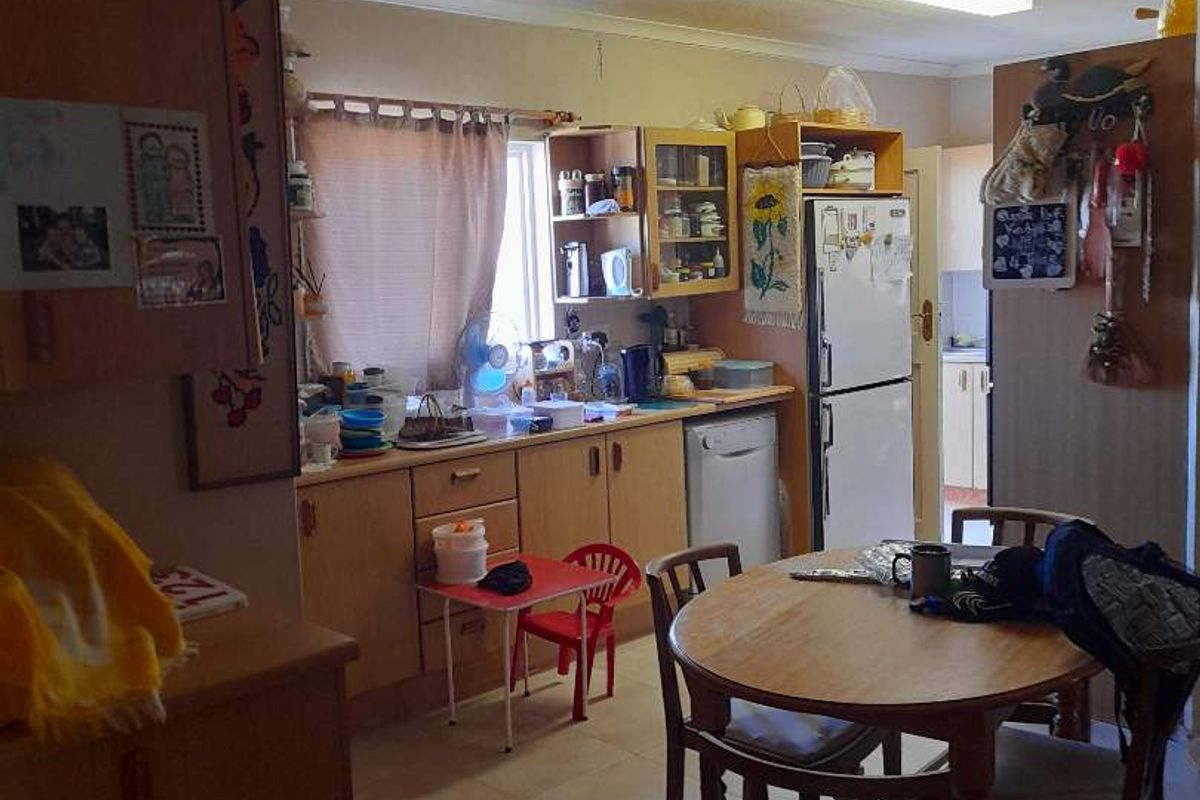 A functional kitchen featuring built-in cabinetry, tiled flooring, and laminate countertops, offering potential for modernization and aesthetic updates.