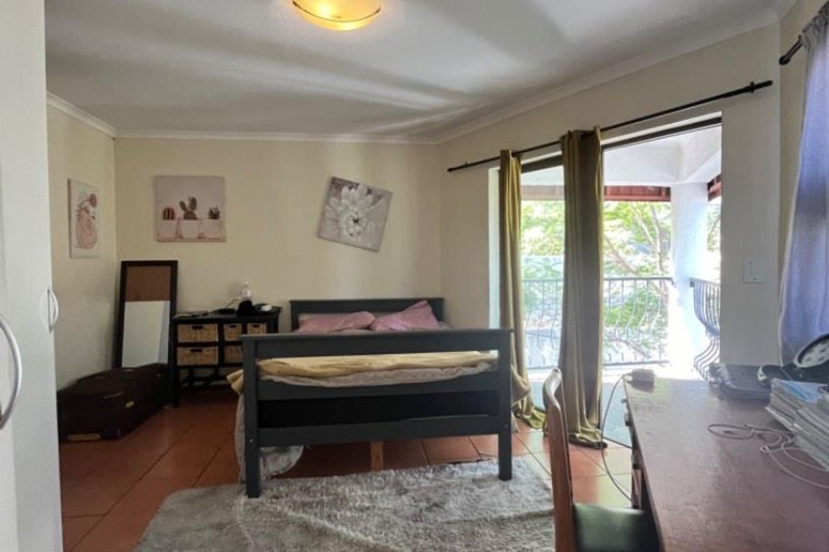 A bedroom featuring terracotta floor tiles, built-in wardrobe, and direct access to a private balcony through sliding glass doors.